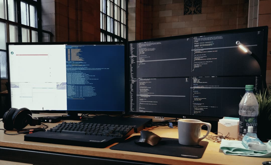 Two large computer monitors on a desk with code editors on each, in a large room.